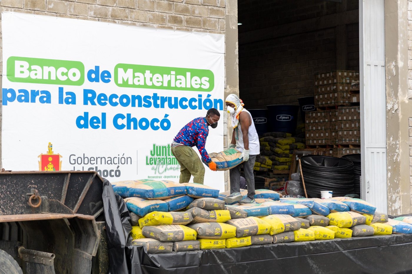 Trabajadores cargando bultos de cemento frente a la bodega del Banco de Materiales para la Reconstrucción del Chocó